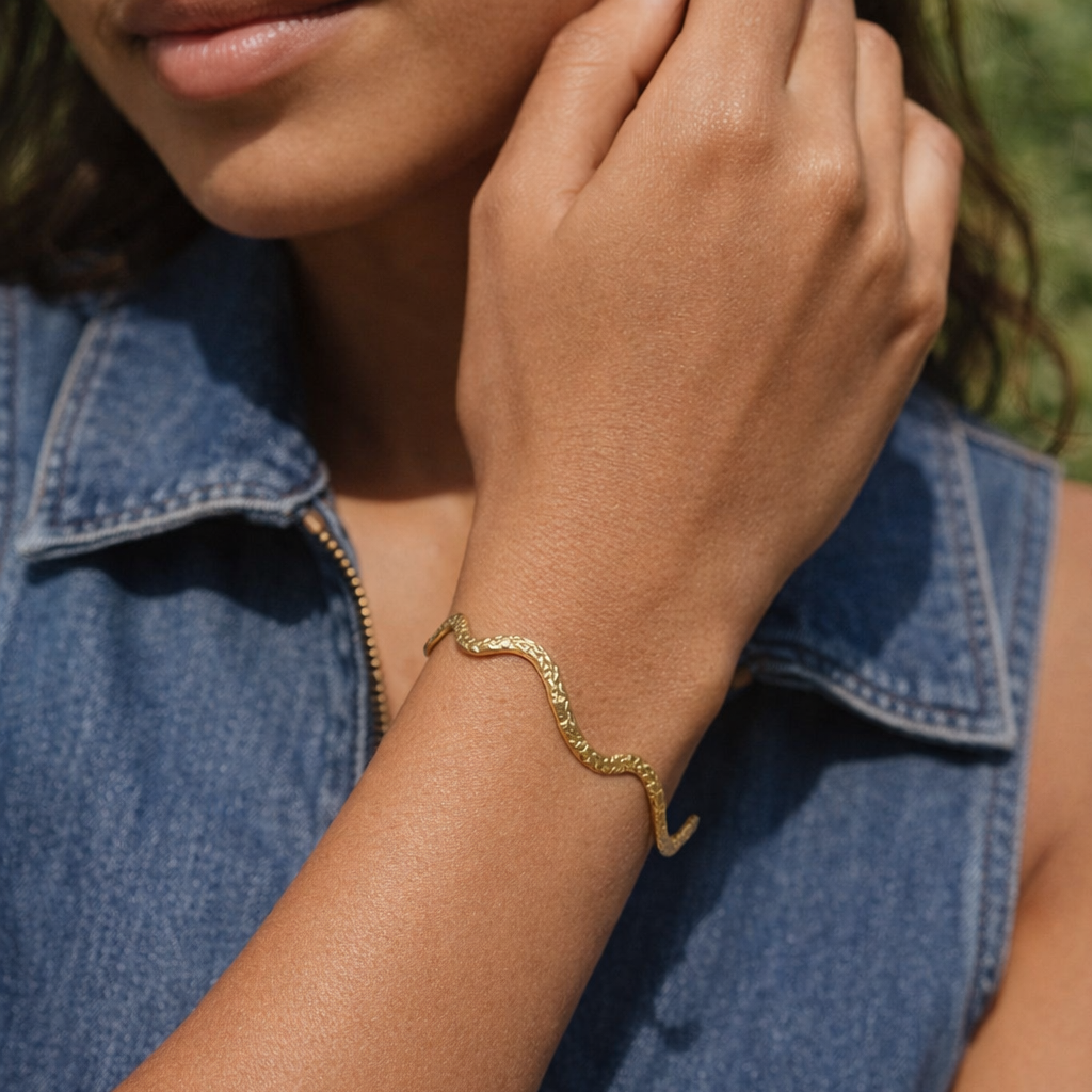 JUNO Gold Cuff, textured open cuff bracelet with organic wave shaped silhouette and hammered finish, featuring soft warm 18k gold tnes and adjustable open-ended design worned alone by model-CCaura