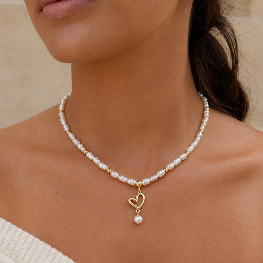 CELESTE PEARL HEART NECKLACE - 18K Gold PVD beads and freshwater pearls necklace with a hanging gold heart charm and pearl drop, worn by model. CCAura
