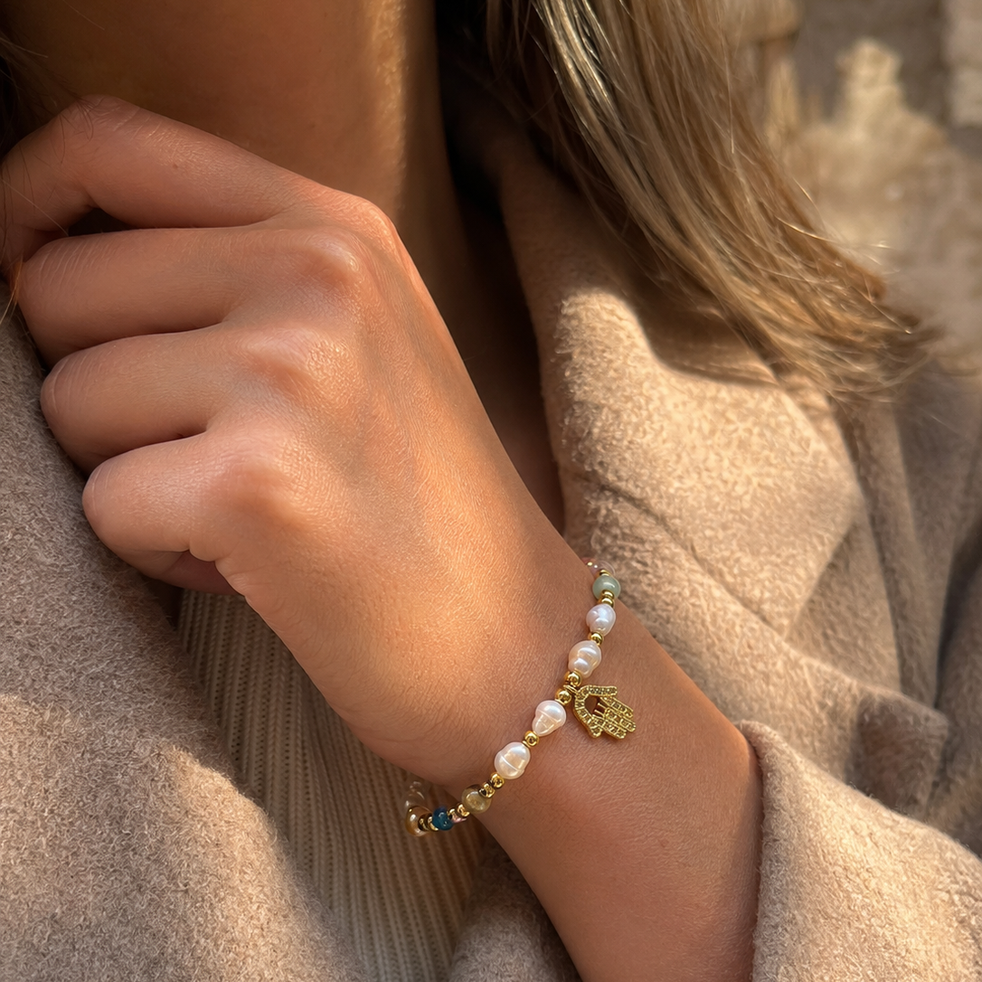 Hamsa Pearl Bracelet close-up, worned on wrist petite gold Hamsa charm with zirconia stones and freshwater pearl detail – CCaura
